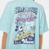 Camiseta celeste de manga corta con cuello redondo y estampado de Mickey Mouse surfeando.