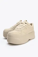Zapatillas deportivas color beige con plataforma alta. Cierre con cordones.