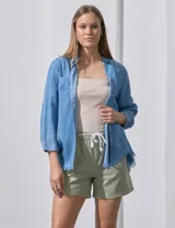 Camisa celeste de tencel con cuello con solapa, escote en V, abertura central con botones, bolsillo aplicado en el frente y ruedo desflecado.