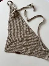 Pañuelo triangular de crochet color beige con tiras para atar.