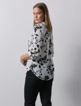 Blusa de gasa estampada con flores, marca Zac & Rachel. Tiene cuello a la base, escote en V y abertura con botones. Las mangas largas son de largo regulable.