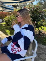 Sweater tejido a mano en hilo de algodón color blanco y azul marino a rayas horizontales, con cuello polo y bordado de cangrejo rojo en el frente.