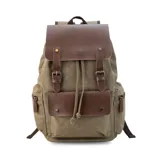 Mochila de tela canvas color verde militar con detalles en símil cuero marrón. Tiene cierre superior con cordón, bolsillos internos y externos con cierre metálico, asas rígidas y correas ajustables. Tiene espacio para laptop de 15 pulgadas.