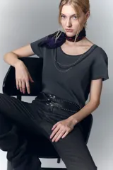 Remera gris de algodón con cuello redondo y aplique de cadenas metálicas y strass en el escote.