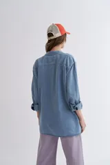 Camisa celeste de jean de manga larga con cuello clásico y cierre frontal con botones.