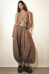 Pantalón bombacho marrón de tejido fluido, tiro medio con cintura elástica ajustable con cordones, bolsillos laterales ocultos y bajo abullonado con elástico interior.