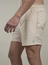 Short de baño verde con estampado de margaritas blancas y cordón ajustable naranja.