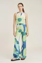 Top corto tipo crop top, sin mangas y con cuello halter. Presenta un estampado grande de flores en tonos verde claro, verde azulado y beige/crema.