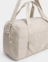 Bolso de tela deportiva color negro, con bolsillo frontal y doble asa corta de mano. Incluye correa regulable y desmontable, cierre superior con tirador de cordón y goma, y tag de goma.