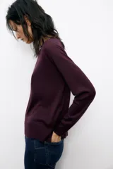 Jersey de punto color verde oliva, con cuello redondo y manga larga. Tiene bajo con aberturas laterales y acabados en rib.