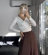 Blusa blanca de poliéster labrado, con cuello drapeado estilo bote y mangas largas.