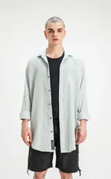 Camisa celeste de manga larga con bolsillo ojal en delantero, cartera escondida y calce oversize.