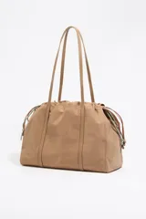 Bolso bandolera grande de nylon color beige, con estructura blanda, doble asa de tejido, logo grabado BIMBA Y LOLA, bolsillo interior con cierre y placa metálica logotipada.