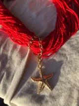 Collar corto de mostacillas rojas con dije de estrella de mar dorada.