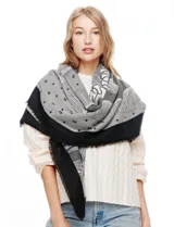 Pashmina grande con estampado tipo patchwork en tonos de gris, blanco y negro. Presenta un borde liso negro y flecos en los extremos.