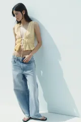 Top amarillo con estampado de cuadros vichy blancos, escote en pico, sin mangas, con detalle de elásticos en la cintura y cierre frontal con lazadas.