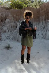 Campera de cuero negra con corte biker, cierre asimétrico, cuello con solapas y flecos en mangas y espalda.