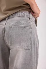 Pantalón de jean gris de corte ancho con bolsillos laterales y pañuelo estampado atado a la cintura.