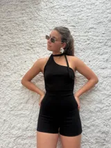 Mono corto negro con escote asimétrico halter y detalle de lazo al cuello.