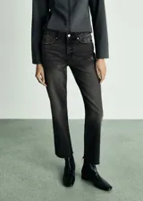 Pantalón de jean negro con lavado gastado, corte recto, tiro medio y terminación desflecada.