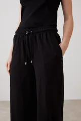 Pantalón verde oliva de corte palazzo con pretina elastizada y cordón ajustable. Incluye bolsillos laterales.