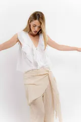Blusa blanca de algodón con escote en V, volados en el frente y mangas cortas.