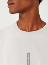 Remera beige de corte recto con estampa vertical en el centro del pecho.