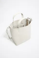 Bolso de mano mediano marca Bimba y Lola, color naranja, confeccionado en cuero con textura granulada. Tiene doble asa corta, correa bandolera ajustable y extraíble, logo estampado en el frente y herrajes plateados. El interior cuenta con etiqueta de tejido con el logo de la marca.