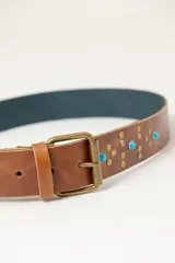 Cinturón marrón de cuero vacuno con hebilla metálica y apliques de tachas y turquesas.