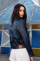 Campera corta de cuero ovino color borgoña, estilo jeanera, con cuello clásico, bolsillos con solapa y cierre frontal con broches metálicos.