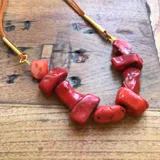 Colgante hecho de piedras rojas irregulares, con cordón de cuero.