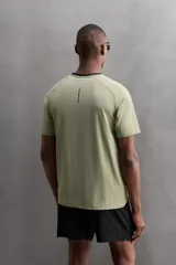 Camiseta deportiva verde militar confeccionada en tejido estructurado, ligero y elástico. Tiene cuello redondo, manga corta y bajo con aberturas laterales. Incluye logo estampado en el bajo.