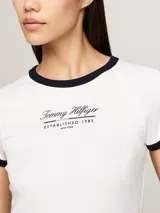 Remera blanca de algodón con cuello redondo y mangas cortas con ribete negro. Logo de Tommy Hilfiger bordado en el pecho.