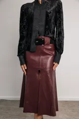 Falda midi color marfil de cuerina, con cierre metálico frontal, cinturón con lazo y abertura delantera.