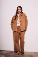 Sobrecamisa negra de gamuza vegana con calce oversize, cuello camisero, cierre con botones a presión, mangas largas con puños abotonados y bolsillos de parche en el pecho.