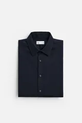 Camisa blanca de corte regular, cuello italiano, manga larga con puños abotonados y cierre frontal con botones.