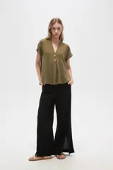 Blusa color crudo de viscosa, corte holgado, con cuello en v y cierre frontal con dos botones de madera.