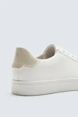 Zapatillas urbanas de cuero sintético negro, con cordones y suela de goma color crema.