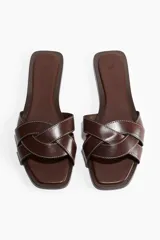 Sandalias de cuero color marrón con punta cuadrada y tiras anchas trenzadas. Tienen un taco de 1 cm y costuras blancas a contraste.