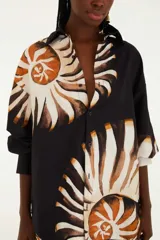 Camisa negra con estampado de amonitas, cuello mao, botones frontales ocultos y mangas largas ligeramente acampanadas.