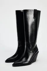 Bota alta negra de cuero sintético, estilo cowboy, con punta fina y tacón geométrico.