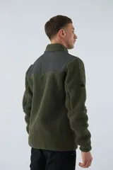 Campera de sherpa verde con detalles en negro, cuello alto, cierre frontal y bolsillo con cierre en el pecho.