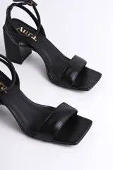 Sandalia de cuero color nude, con tira delgada sobre los dedos, pulsera al tobillo con hebilla y tacón cuadrado.