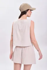 Top sin mangas color crudo con rayas verticales finas en color beige, escote en V con lazos ajustables y corte crop.