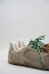 Zapatillas urbanas de cuero color tostado, con cordones verdes y suela de goma.