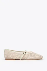 Zapato plano tipo bailarina color beige, con cuerpo de mesh bordado con flores y perlas, tira delantera con hebilla y punta redonda.