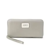 Billetera larga negra con cierre perimetral y placa metálica con logo. Posee múltiples compartimentos internos para tarjetas y documentos, además de un bolsillo con cierre interior. Incluye correa de mano desmontable.