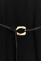 Vestido negro de tejido de punto, corte midi y silueta holgada, con cuello alto acanalado y mangas cortas tipo murciélago. Se ajusta a la cintura con un cinturón fino de efecto piel negro con hebilla dorada en forma de C.