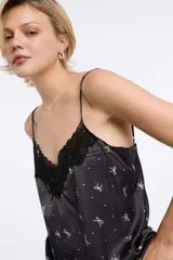 Musculosa con estampado animal print en tonos negro, blanco y verde oliva, con escote en V y detalle de encaje negro en el borde. Tirantes finos ajustables.