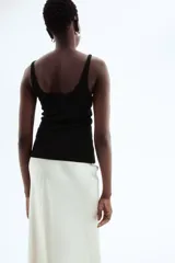 Musculosa negra de punto acanalado, corte entallado, con escote redondo tanto en la parte delantera como en la trasera.
